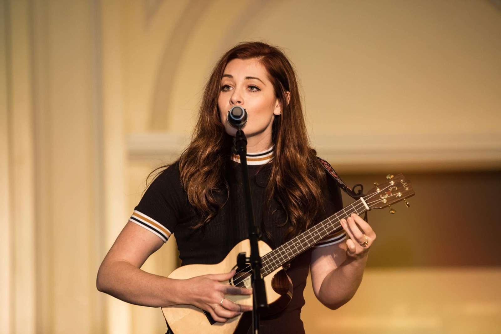 Mandy Harvey plays the ukulele while singing into a microphone